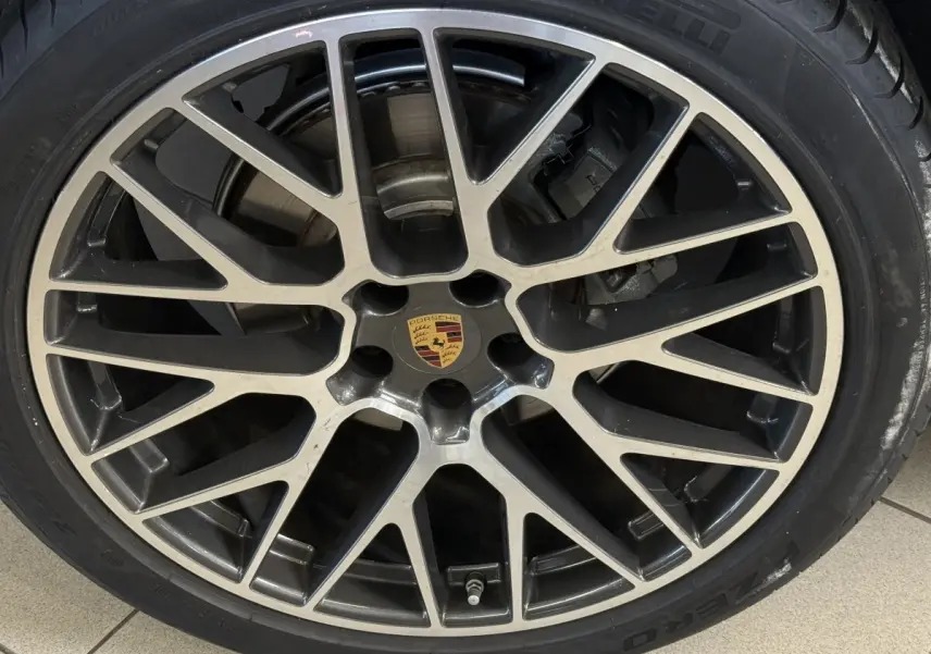 Gros plan sur la jante alliage bicolore avec logo Porsche au centre, montée sur pneu Pirelli.