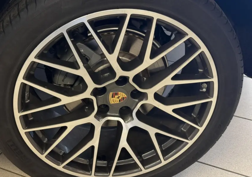 Gros plan sur la jante alliage bicolore avec logo Porsche du SUV gris foncé Porsche Macan 3.0 S 2019.