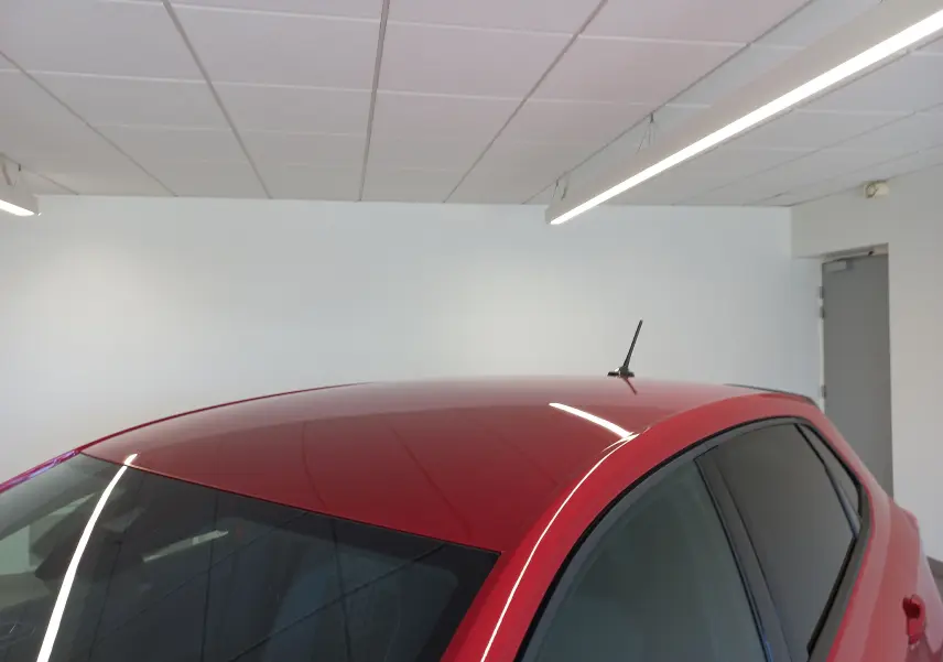 Toit et partie supérieure côté gauche d'une Volkswagen Polo Rouge Roi 2025 en intérieur, avec antenne de toit visible.