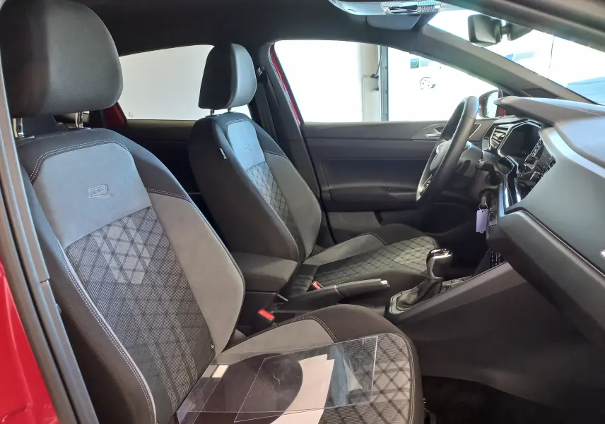 Vue intérieure côté conducteur de la Volkswagen Polo 2025 Rouge Roi, sièges R-Line avec surpiqûres et motifs géométriques.