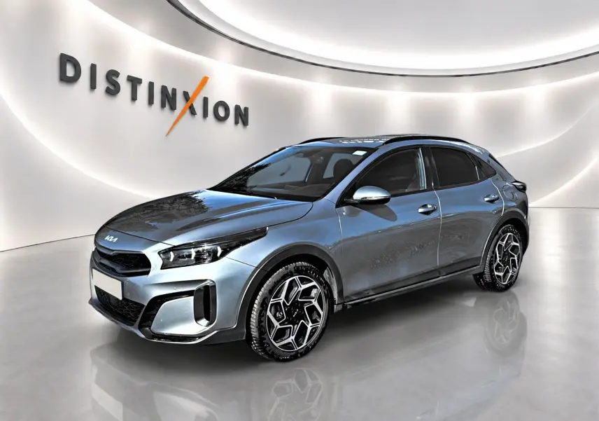 KIA Xceed gris en vue 3/4 avant droit, avec jantes alu distinctives et calandre chromée dans un showroom lumineux.