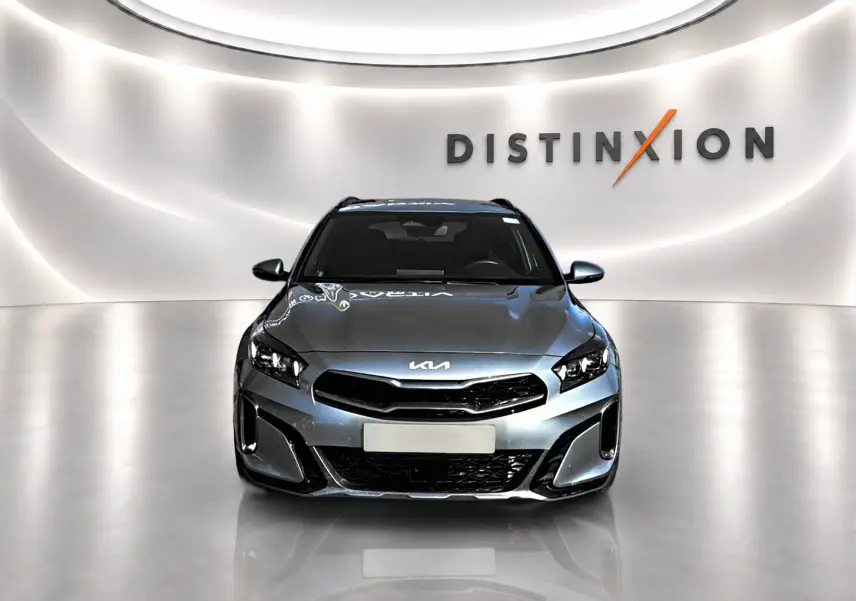 Vue avant d'un KIA Xceed gris 2024 avec calandre noire et phares LED dans un showroom lumineux.