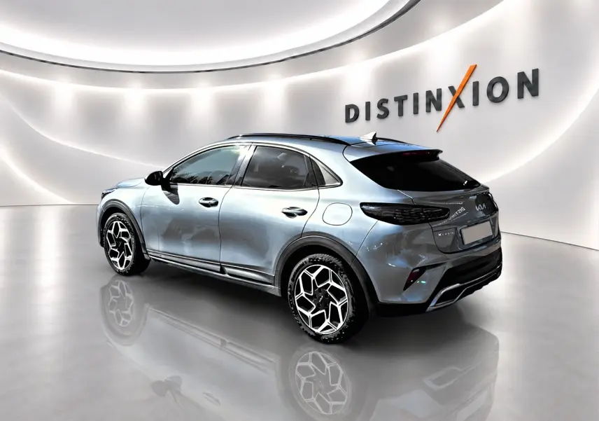 KIA Xceed gris 3/4 arrière droit en showroom avec jantes alu au design hexagonal et vitres surteintées.