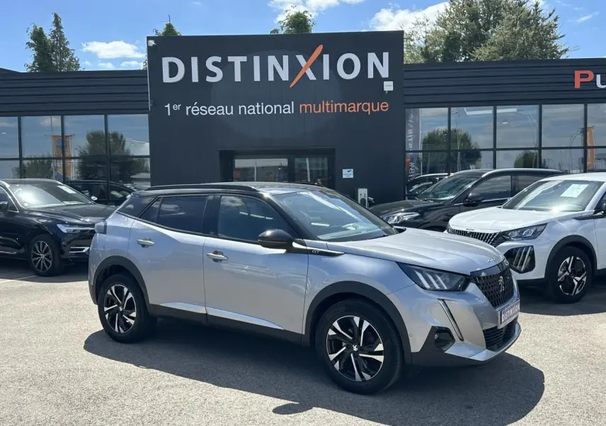 Peugeot 2008 gris Artense avec toit noir en 3/4 avant droit, jantes bi-ton et barres de toit noir brillant.