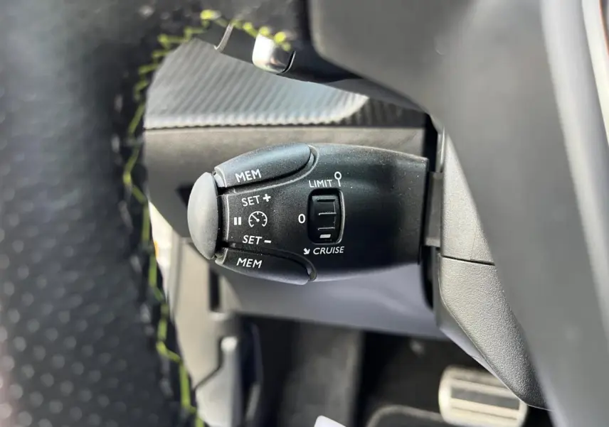 Gros plan sur la commande de régulateur de vitesse du Peugeot 2008 II gris Artense avec volant partiellement visible.
