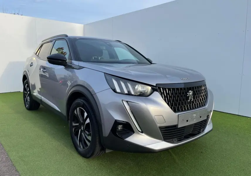Peugeot 2008 gris Artense avec toit noir, vue 3/4 avant droit, jantes bi-ton et barres de toit noir brillant.