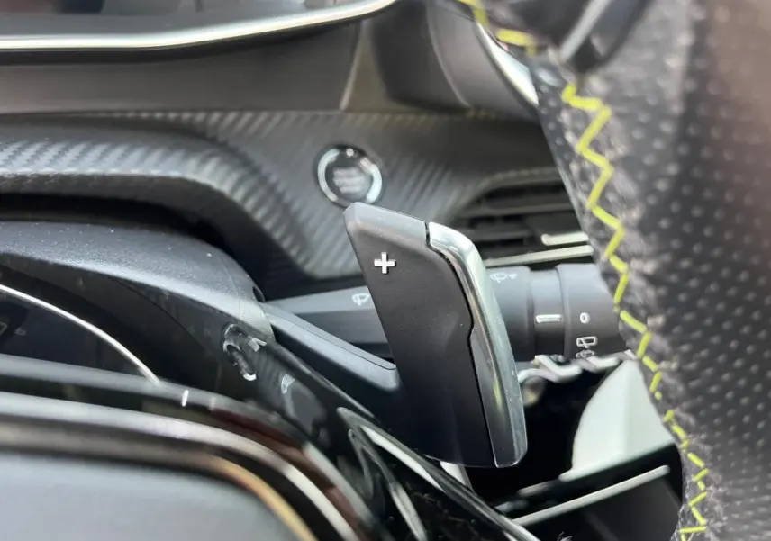 Gros plan sur la palette de passage de vitesses "+" à droite du volant perforé avec surpiqûres jaunes du Peugeot 2008 gris Artense.