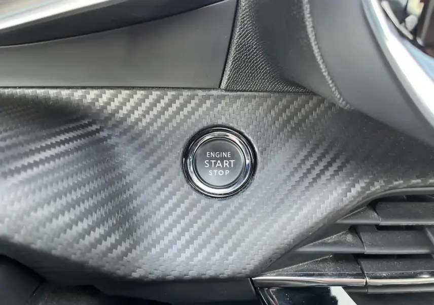 Bouton start/stop sur tableau de bord effet carbone du Peugeot 2008 II GT avec finition intérieure noire.
