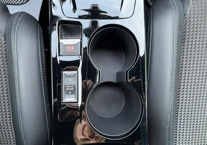 Gros plan sur la console centrale noire brillante avec porte-gobelets et commandes Drive Mode du Peugeot 2008 gris Artense.