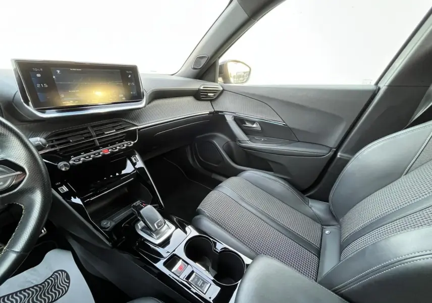 Intérieur avant droit du Peugeot 2008 II gris, avec tableau de bord numérique et console centrale brillante noire.