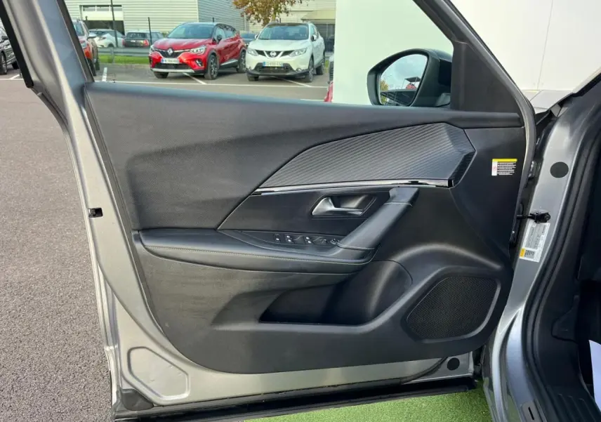 Gros plan sur la porte avant gauche gris Artense du Peugeot 2008 II, avec garniture noire et insert effet carbone.