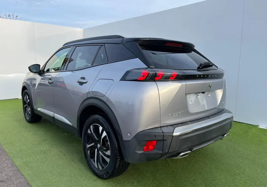 Peugeot 2008 gris Artense avec toit noir, vue 3/4 arrière droit, feux arrière LED 3 griffes et jantes bi-ton 17 pouces.