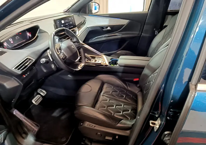 Vue intérieure côté conducteur du Peugeot 5008 bleu 2021, sièges cuir noirs et tableau de bord digital moderne