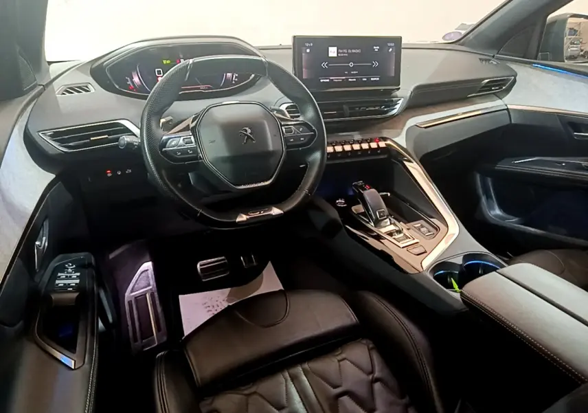 Intérieur Peugeot 5008 GT 2021 vu côté conducteur, volant compact, écran tactile central et sellerie cuir noire.