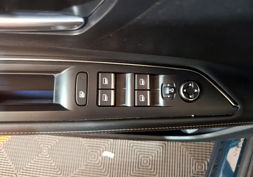 Commande des vitres et rétroviseurs côté gauche en cuir noir avec surpiqûres sur Peugeot 5008 bleu, vue intérieure rapprochée.