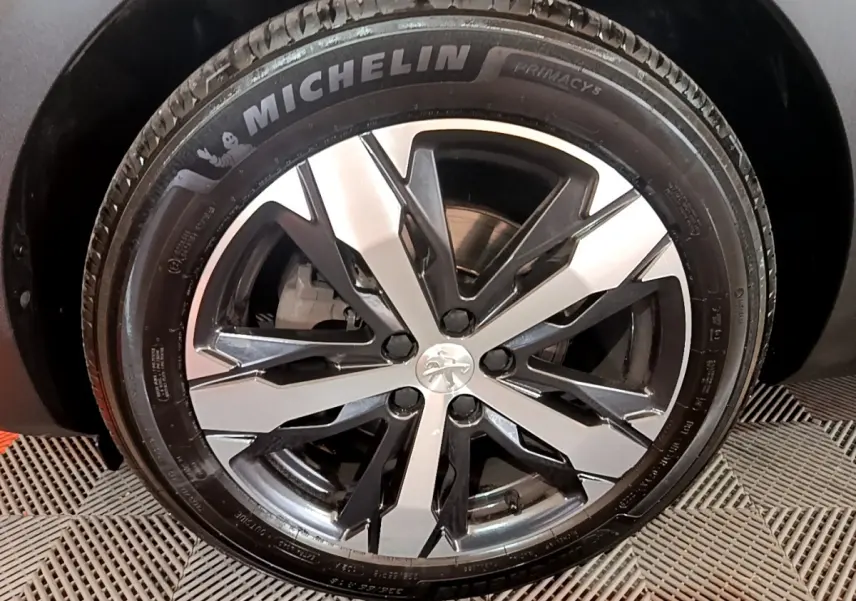 Gros plan sur la jante alliage bicolore et pneu Michelin d'un Peugeot 5008 bleu, côté gauche.