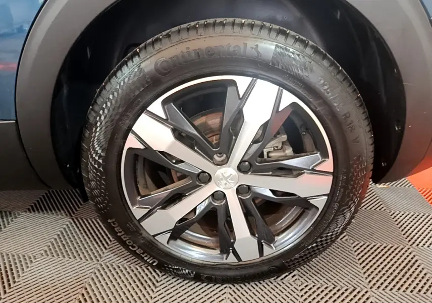 Gros plan sur la roue avant droite du Peugeot 5008 bleu, mettant en valeur la jante alliage et le pneu Continental.