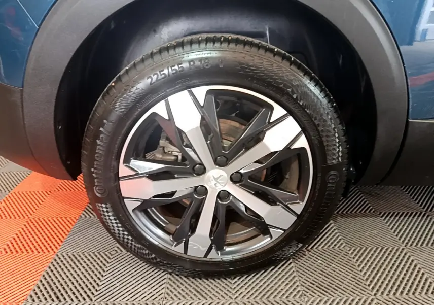 Gros plan sur la roue avant droite du Peugeot 5008 bleu, mettant en valeur la jante alliage bicolore et le pneu Continental.