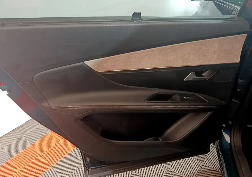 Vue intérieure côté gauche de la porte arrière du Peugeot 5008 bleu, avec garniture noire et beige élégante.