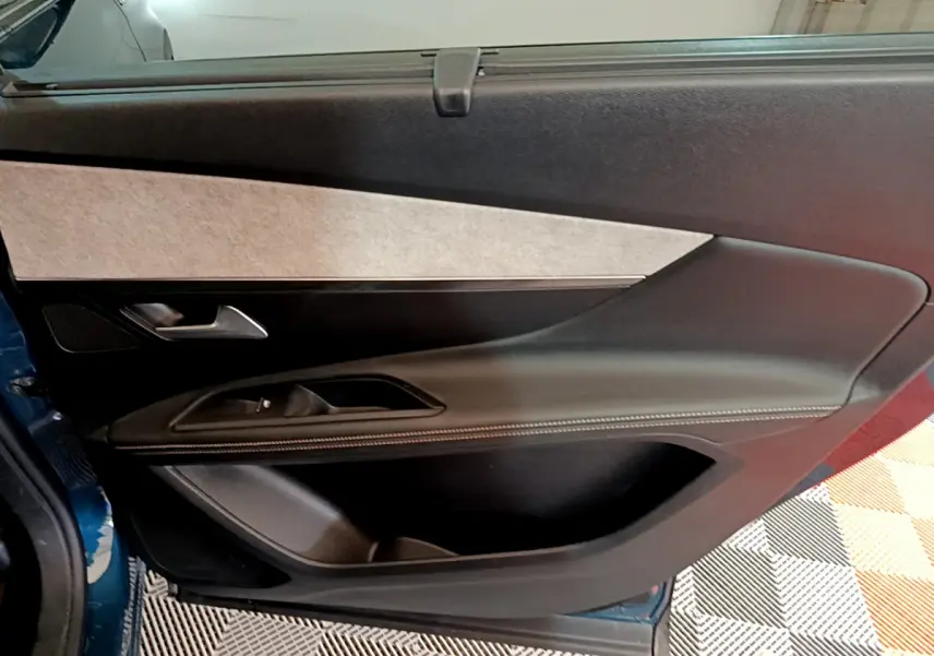 Porte intérieure côté gauche du Peugeot 5008 GT bleu 2021, avec garniture noire et surpiqûres blanches.