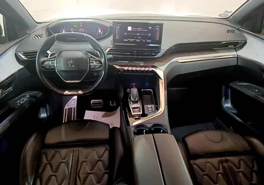 Intérieur Peugeot 5008 GT vu de face, tableau de bord moderne avec écran tactile et volant cuir noir.