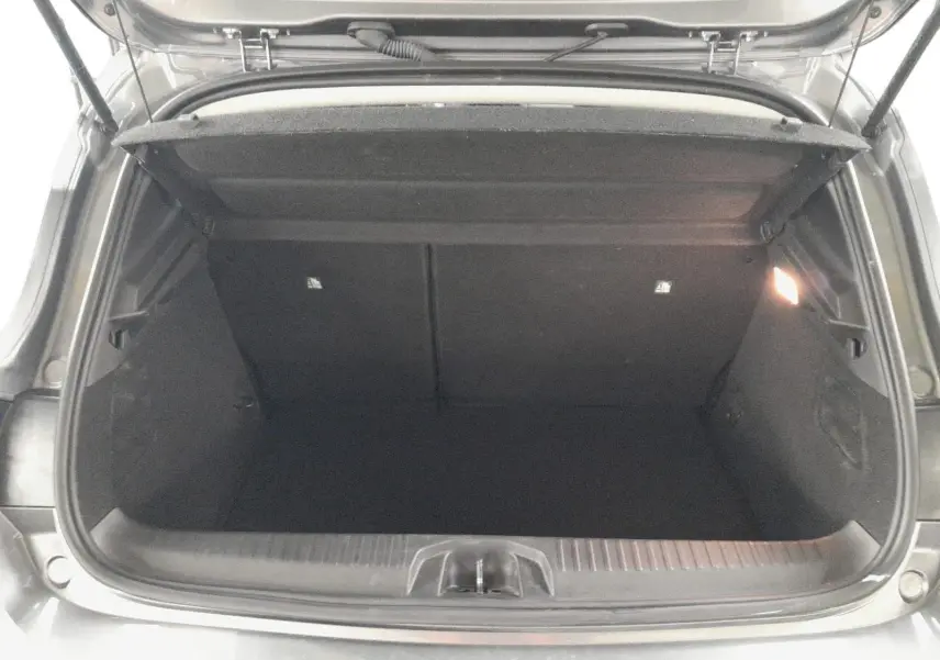 Coffre ouvert vu de l'arrière d'une Renault Clio V gris schiste, montrant l'espace de rangement vide et l'éclairage intérieur.