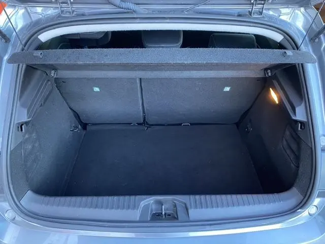 Vue intérieure du coffre ouvert d'une Renault Clio V gris schiste, montrant l'espace de rangement et l'éclairage latéral droit.