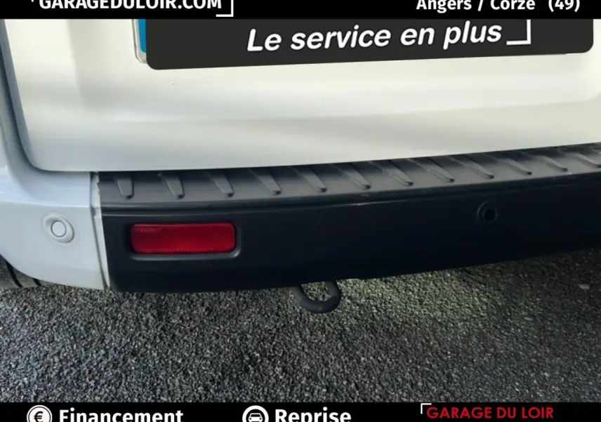 Gros plan sur le pare-chocs arrière noir et la partie basse blanche du Ford Transit Custom Fourgon blanc, avec feu rouge et crochet d’attelage visible.
