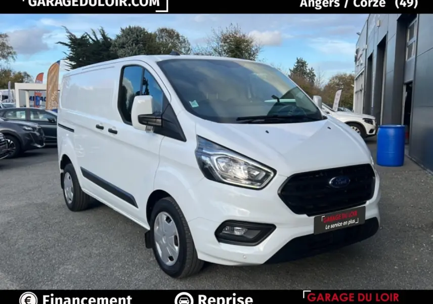 Vue 3/4 avant droit d'un Ford Transit Custom fourgon blanc avec calandre noire et feux LED, stationné en extérieur.