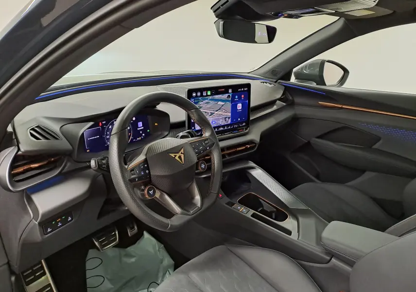 Vue intérieure côté conducteur du CUPRA TERRAMAR 2025, tableau de bord moderne avec écran tactile et éclairage d'ambiance bleu.