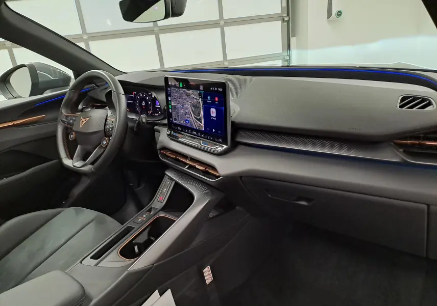 Vue intérieure côté conducteur du tableau de bord du CUPRA TERRAMAR 2025 avec écran tactile et éclairage d'ambiance bleu.