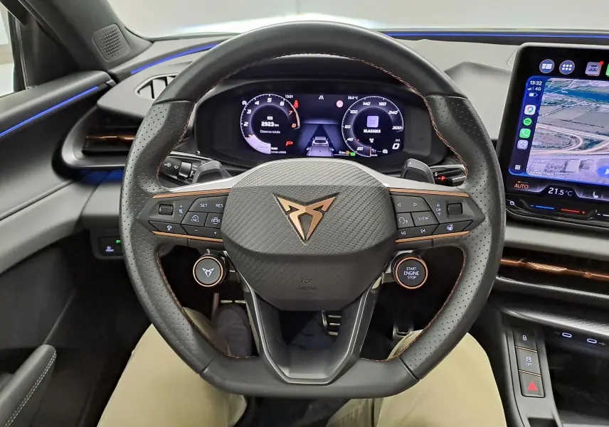 Vue intérieure centrée sur le volant perforé du CUPRA TERRAMAR 2025 avec tableau de bord numérique et écran tactile latéral.