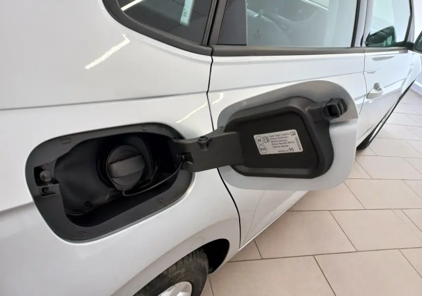 Vue latérale gauche rapprochée d’une Volkswagen Polo argent avec trappe à carburant essence ouverte sur un sol carrelé.
