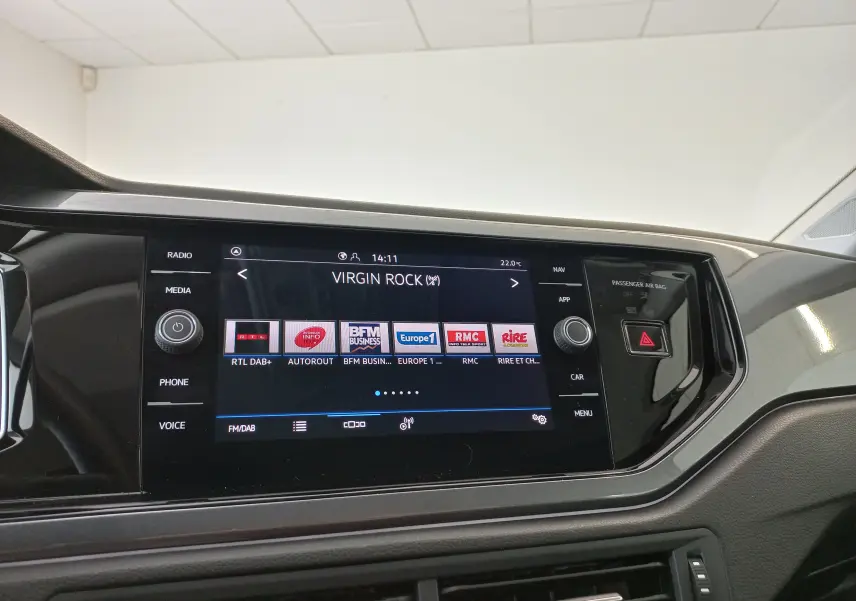 Écran tactile central de la Volkswagen Polo 2026 affichant la radio Virgin Rock, avec commandes autour et bouton de signal d'alerte.