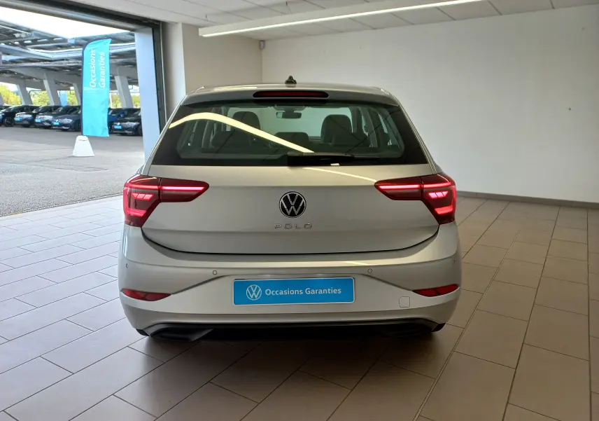 Vue arrière d'une Volkswagen Polo 2026 couleur reflet d'argent, avec feux arrière allumés dans un garage.