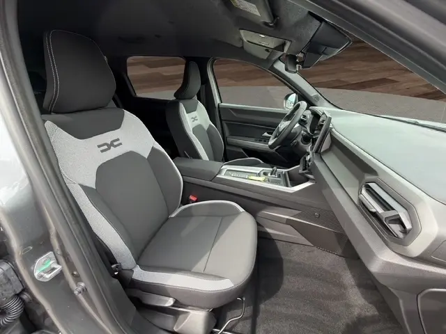 Vue intérieure côté conducteur du Dacia Bigster Journey Hybrid gris foncé, avec sièges tissu bi-ton et tableau de bord moderne.