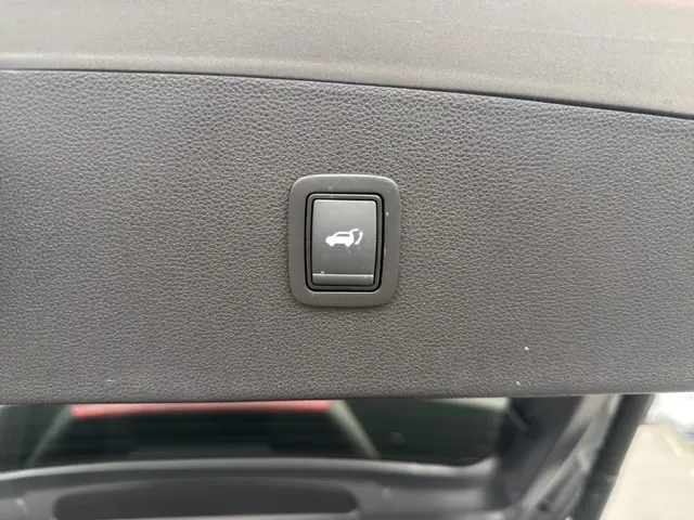 Bouton noir d'ouverture électrique du coffre sur le hayon intérieur gris foncé du Dacia Bigster Journey Hybrid 2026.