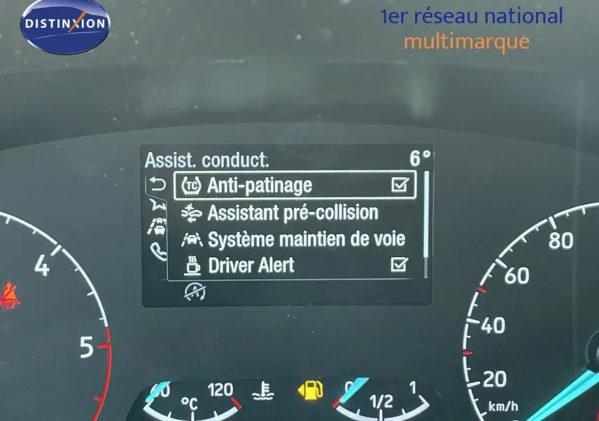 Tableau de bord du Ford Transit Fourgon blanc 2023 montrant l'écran d'assistance à la conduite et compteurs analogiques.