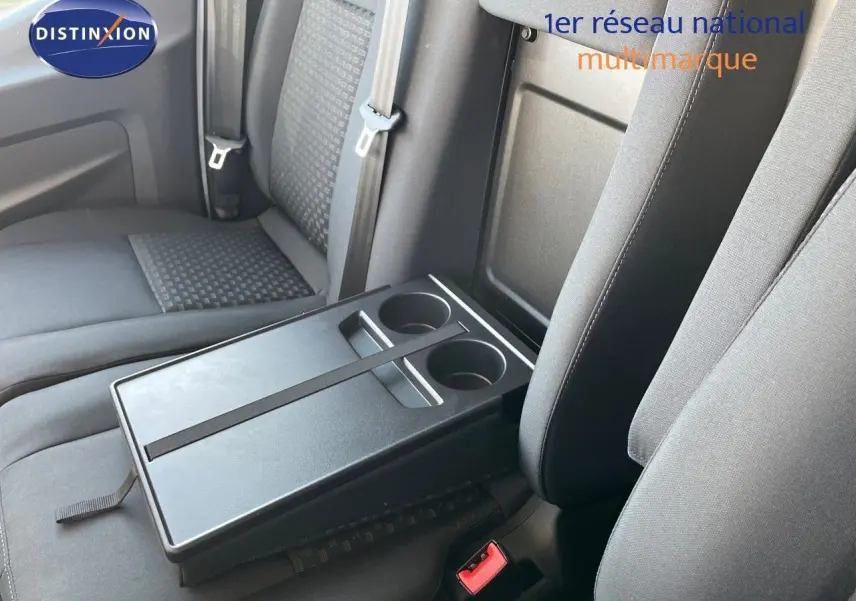 Détail intérieur montrant la banquette grise avec tablette rabattable et porte-gobelets du Ford Transit Fourgon blanc 2023.