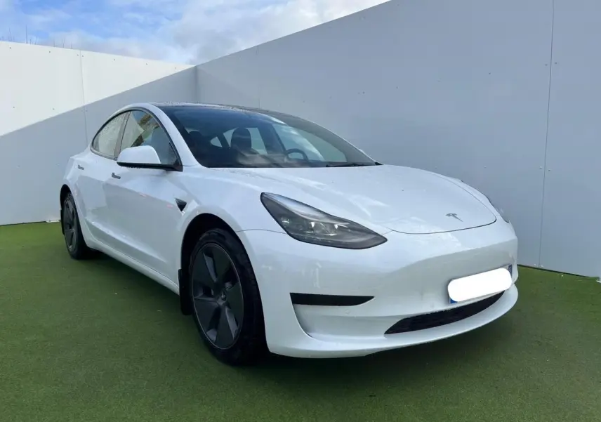 Tesla Model 3 blanc vue 3/4 avant droit, avec jantes noires et toit panoramique en verre visible.