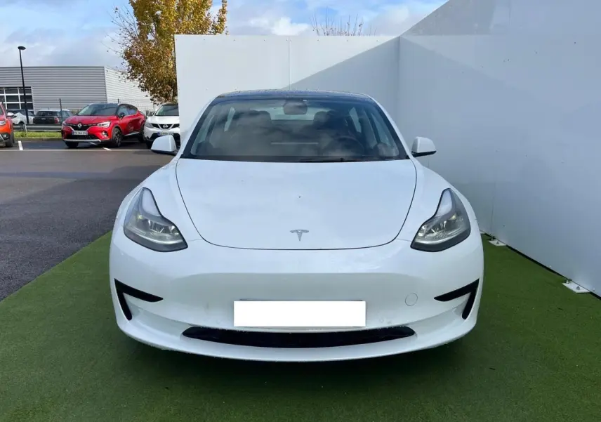 Vue frontale d'une Tesla Model 3 blanche électrique 2022, avec phares LED et capot lisse sans calandre.