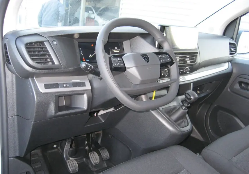 Vue intérieure côté conducteur du Peugeot Expert Fourgon blanc 2025, volant multifonction et boîte manuelle visibles.