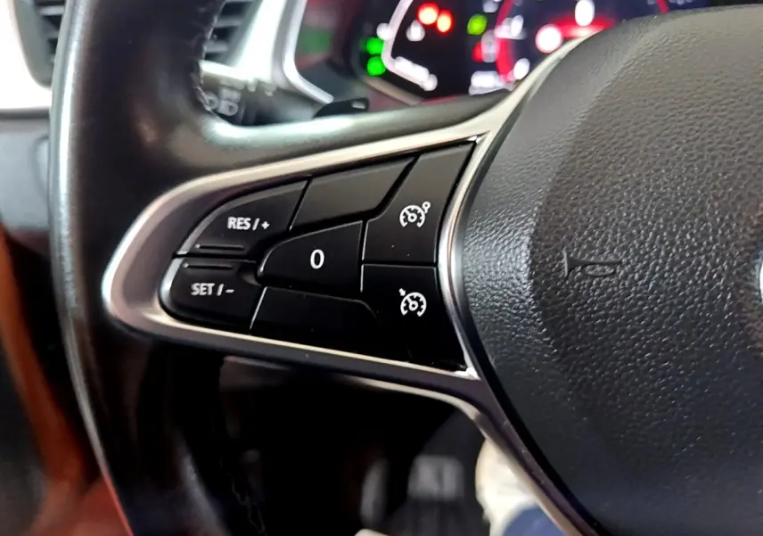 Gros plan sur les commandes de régulateur de vitesse au volant cuir noir du Renault Captur jaune, version Intens 2020.