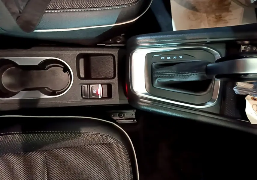 Vue plongeante sur la console centrale noire du Renault Captur Intens, avec levier de boîte auto et porte-gobelets.