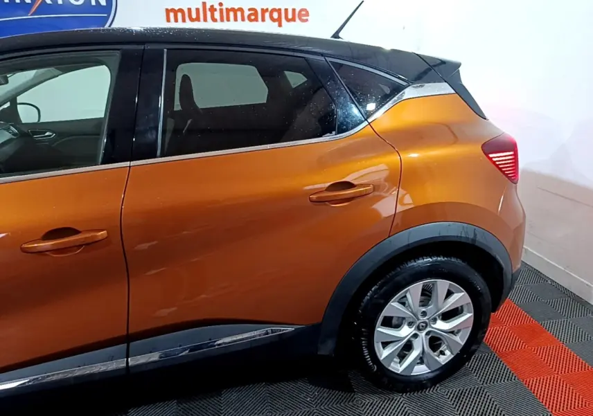 Vue latérale droite du Renault Captur Intens jaune avec toit noir et jantes alliage visibles sur fond intérieur.
