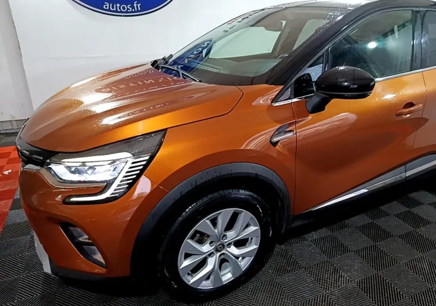 Vue 3/4 avant droit d'un Renault Captur orange métallisé avec phares LED et rétroviseurs noirs.