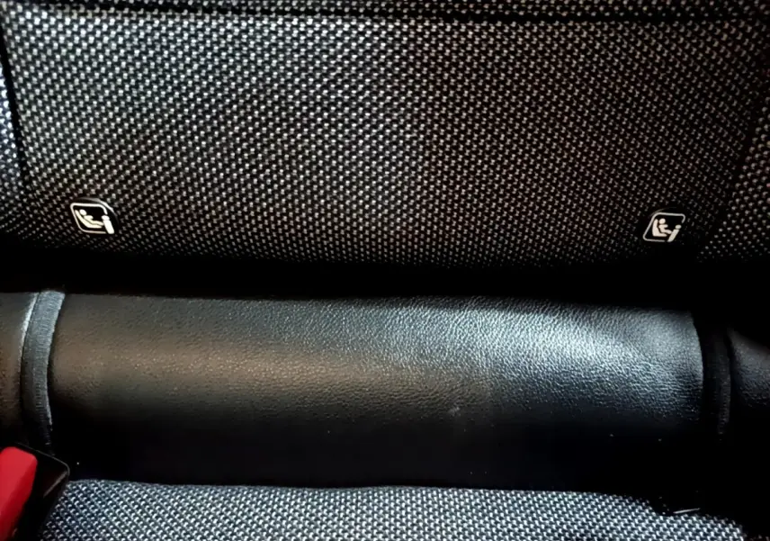 Gros plan sur la banquette arrière noire du Renault Captur Intens, montrant les fixations Isofix et la ceinture rouge.