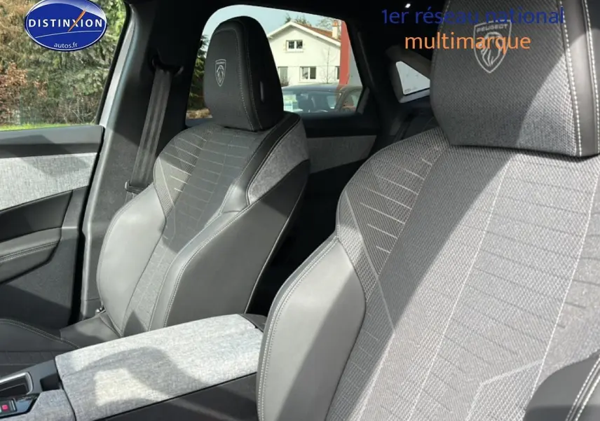 Gros plan sur les sièges avant gris et noirs du Peugeot 3008 1.2 Hybrid 145 GT, avec logo Peugeot brodé sur les appuie-tête.