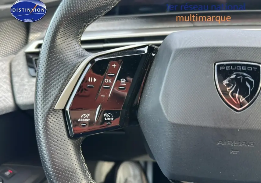 Gros plan sur le volant cuir perforé gris du Peugeot 3008 2025 avec commandes multifonctions et logo lion central.