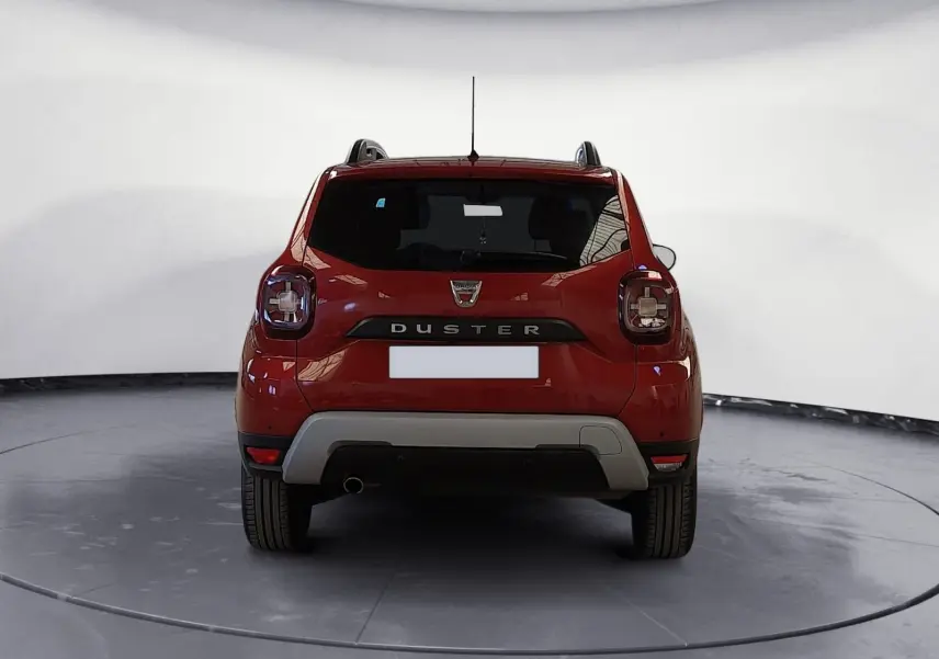 Vue arrière d'un Dacia Duster rouge fusion 2021 avec logo et feux arrière caractéristiques bien visibles.